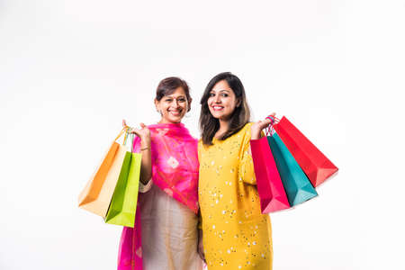 Indian Mother daughter sisters shopping with colourful bags, standing isolated over white backgroundの写真素材