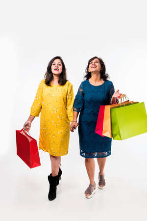 Indian Mother daughter sisters shopping with colourful bags, standing isolated over white backgroundの写真素材