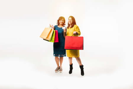 Indian Mother daughter sisters shopping with colourful bags, standing isolated over white backgroundの写真素材