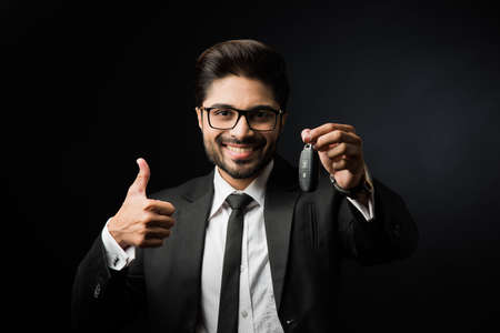 Indian businessman with Car Keys, standing isolated over black backgroundの写真素材