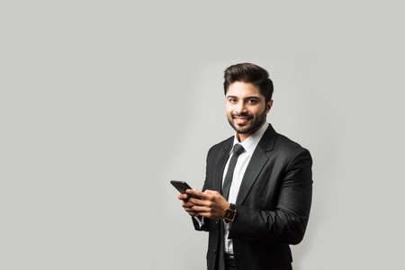 Indian business man using cell phone. Having Conversation, typing sms or presentingの写真素材