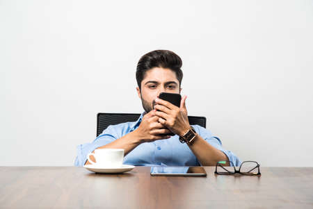 Indian business man using cell phone. Having Conversation or typing or checking social media feeds