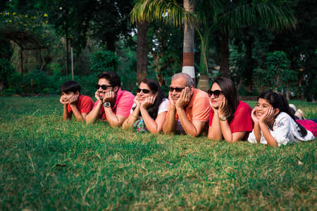 Beautiful Indian multi generation family of six, looking at camera and smiling while lying together...