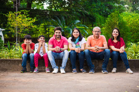 Indian Family enjoying Picnic - Multi generation of asian family sitting over or near small wall in...