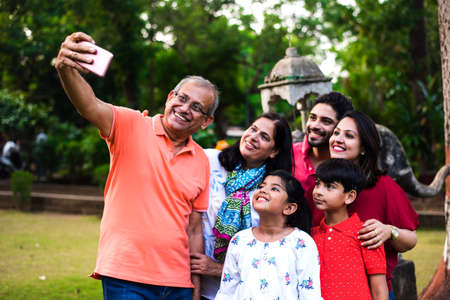 Indian Grandfather taking selfie - multi generation asian family of six, capturing family photograph...