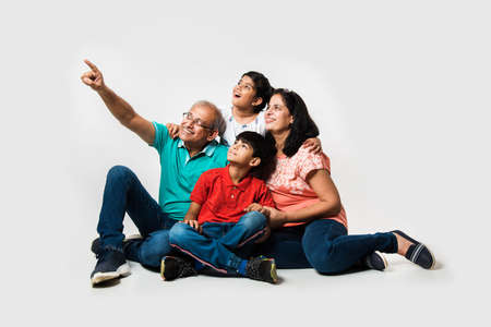 Indian Kids with grandparents smiling while sitting on a white background indoors, selective focusの写真素材