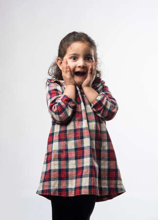 Happy  Indian Little kid girl with open mouth looking with surprised expressions. Standing isolated over white backgroundの写真素材