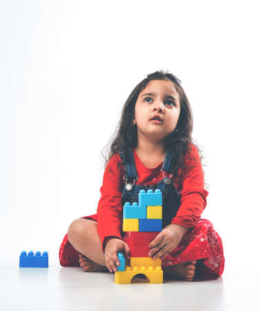 Cute Little Indian  girl playing with colourful block toys over white backgroundの写真素材