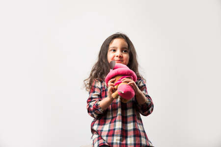 Indian small girl playing with soft toy, isolated over white backgroundの写真素材