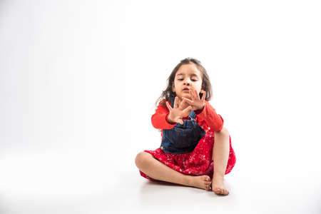 Indian small girl sitting over white floorの写真素材
