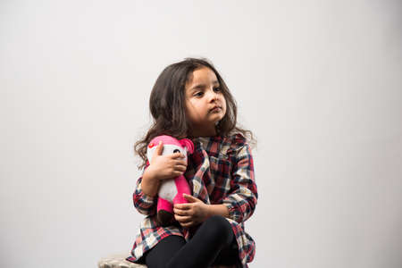 Indian small girl playing with soft toy, isolated over white backgroundの写真素材