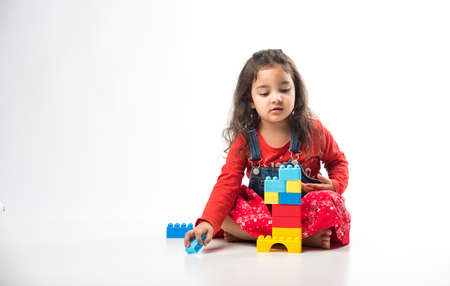 Cute Little Indian girl playing with colourful block toys over white backgroundの写真素材
