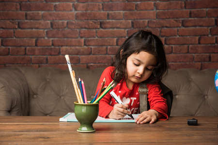 Indian small girl drawing / Painting with colours over paper, selective focus