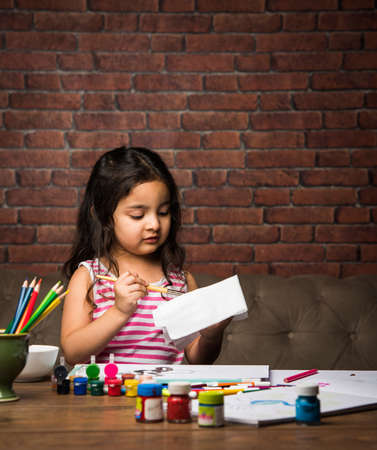 Indian small girl  Painting with colours over paper, selective focusの写真素材