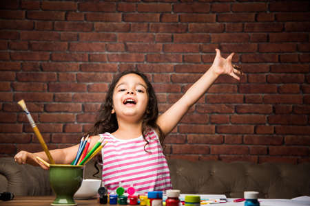 Indian small girl drawing / Painting with colours over paper, selective focusの写真素材