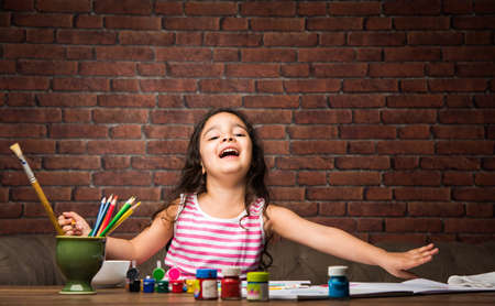 Indian small girl drawing / Painting with colours over paper, selective focusの写真素材
