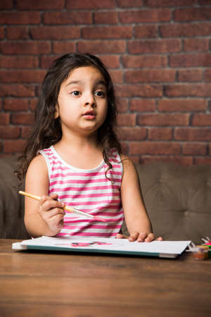 Indian small girl Painting with colours over paper, selective focusの写真素材