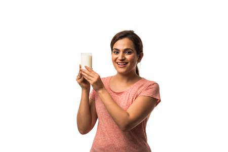 Portrait young Indian/asian woman drinking milk from the glass isolated over white backgroundの写真素材