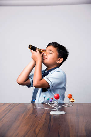 Indian School Kid studying Planets or planetary science with 3d Model of our solar systemの写真素材
