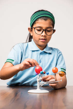 Indian Schoolgirl / girl child studying Planets or planetary science with 3d Model of our solar systemの写真素材