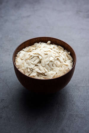 Raw Flattened Rice or Thick or thin Rice Flakes for Namkeen Chivda snacks or Aloo Poha for Indian Breakfast, served in a bowlの写真素材