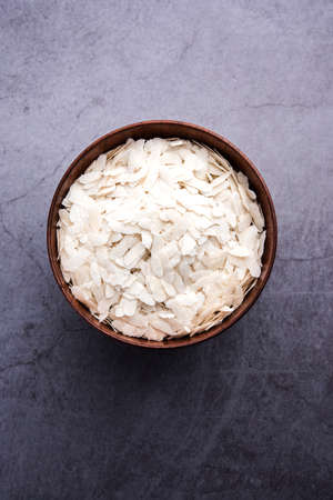 Raw Flattened Rice or Thick or thin Rice Flakes for Namkeen Chivda snacks or Aloo Poha for Indian Breakfast, served in a bowlの写真素材