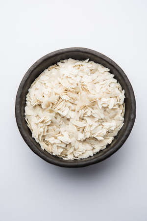 Raw Flattened Rice or Thick or thin Rice Flakes for Namkeen Chivda snacks or Aloo Poha for Indian Breakfast, served in a bowlの写真素材