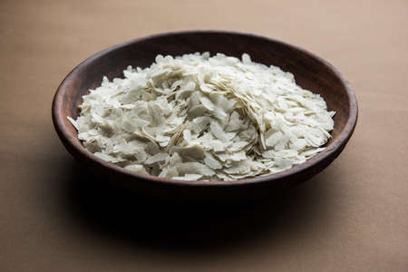 Raw Flattened Rice or Thick or thin Rice Flakes for Namkeen Chivda snacks or Aloo Poha for Indian Breakfast, served in a bowlの写真素材