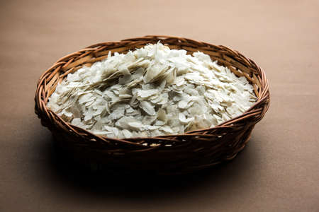 Raw Flattened Rice or Thick or thin Rice Flakes for Namkeen Chivda snacks or Aloo Poha for Indian Breakfast, served in a bowlの写真素材
