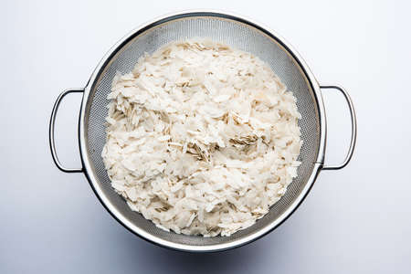 Raw Flattened Rice or Thick or thin Rice Flakes for Namkeen Chivda snacks or Aloo Poha for Indian Breakfast, served in a bowlの写真素材