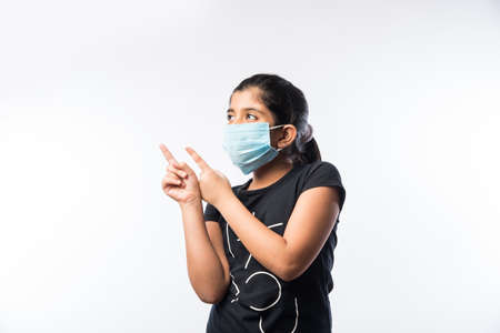 Indian Girl Child Wears Medical Face Mask as a safety measure against Pollution or Virus Spread, standing isolated against white backgroundの写真素材