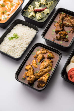 Online Food delivery concept Indian paneer butter masala and palak paneer, mutton & chicken curry with roti and rice in plastic containers, food like butter chicken, chickenの写真素材