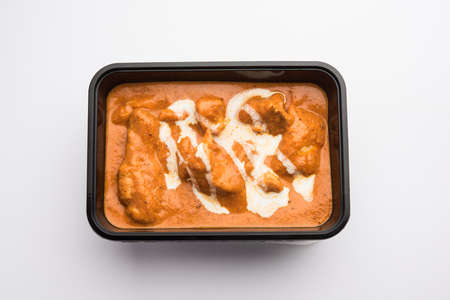 Indian butter chicken curry dish served in black plastic container for food delivery to homeの写真素材