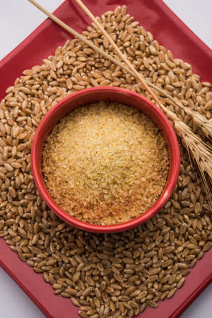 Gehu Dalia or Daliya also known as Cracked or Broken Wheat, served in a bowl or spoon, healthy Indian foodの写真素材