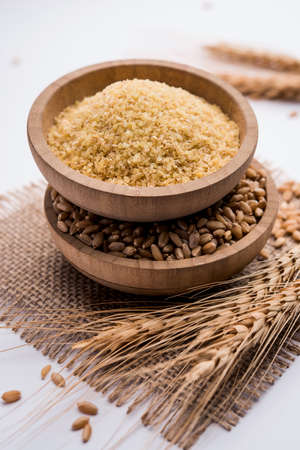 Gehu Dalia or Daliya also known as Cracked or Broken Wheat, served in a bowl or spoon, healthy Indian foodの写真素材