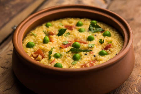 Vegetable Dalia or Daliya Khichadi or Broken Wheat Khichdi with tomato, green peas and chilli,...