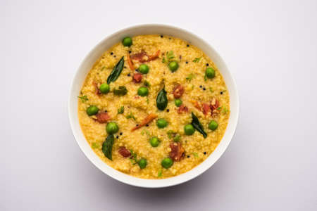 Vegetable Dalia or Daliya Khichadi or Broken Wheat Khichdi with tomato, green peas and chilli, served in a bowl or plateの写真素材