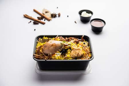 Restaurant style Chicken Tikka Biryani packed for home delivery in plastic box or container with Raita and salanの写真素材