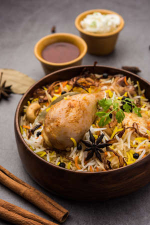 Restaurant style Spicy Chicken Biryani in wooden bowl with Raita and salan, Popular Indian or Pakistani Foodの写真素材