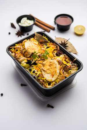 Restaurant style Egg Biryani or Anda Pulao packed for home delivery in plastic box or container with Raita and salanの写真素材