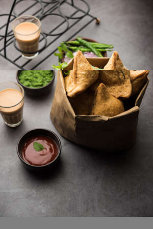 Samosa - Triangle shape fried / baked pastry with savoury filling, popular Indian Tea Time snacks, served with green chutney, tomato ketchupの写真素材
