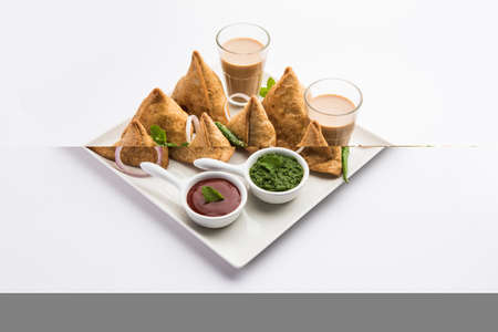 Samosa - Triangle shape fried / baked pastry with savoury filling, popular Indian Tea Time snacks, served with green chutney, tomato ketchupの写真素材