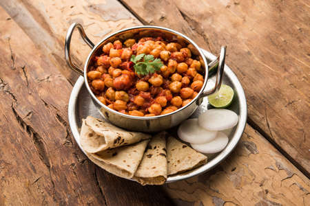 Spicy Chickpea curry, Chana Masala or Choley in bowl with chapati and salad. Traditional North Indian dish.の写真素材