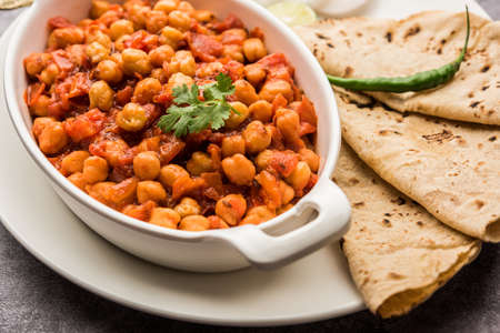 Spicy Chickpea curry, Chana Masala or Choley in bowl with chapati and salad. Traditional North Indian dish.の写真素材