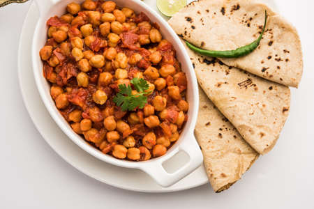 Spicy Chickpea curry, Chana Masala or Choley in bowl with chapati and salad. Traditional North Indian dish.の写真素材