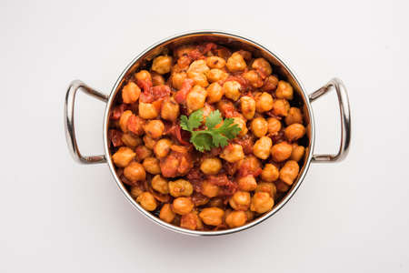 Spicy Chickpea curry, Chana Masala or Choley in bowl with chapati and salad. Traditional North Indian dish.の写真素材