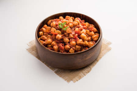 Spicy Chickpea curry, Chana Masala or Choley in bowl with chapati and salad. Traditional North Indian dish.の写真素材