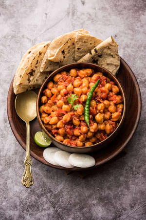 Spicy Chickpea curry, Chana Masala or Choley in bowl with chapati and salad. Traditional North Indian dish.の写真素材