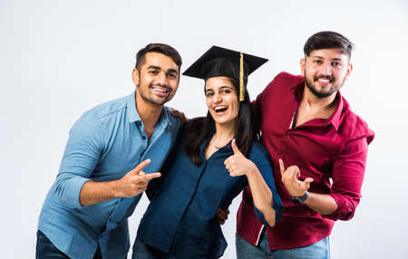 Beautiful young Graduate Indian girl student celebrating success with male friend while wearing...