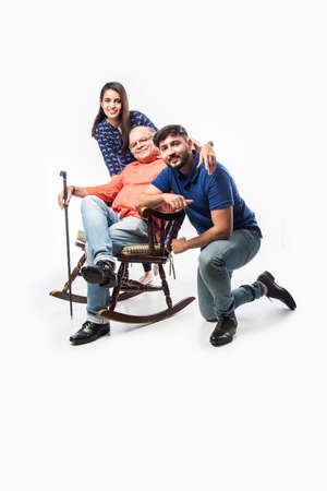 Indian old man or father with young son and daughter, sitting over rocking chairの写真素材